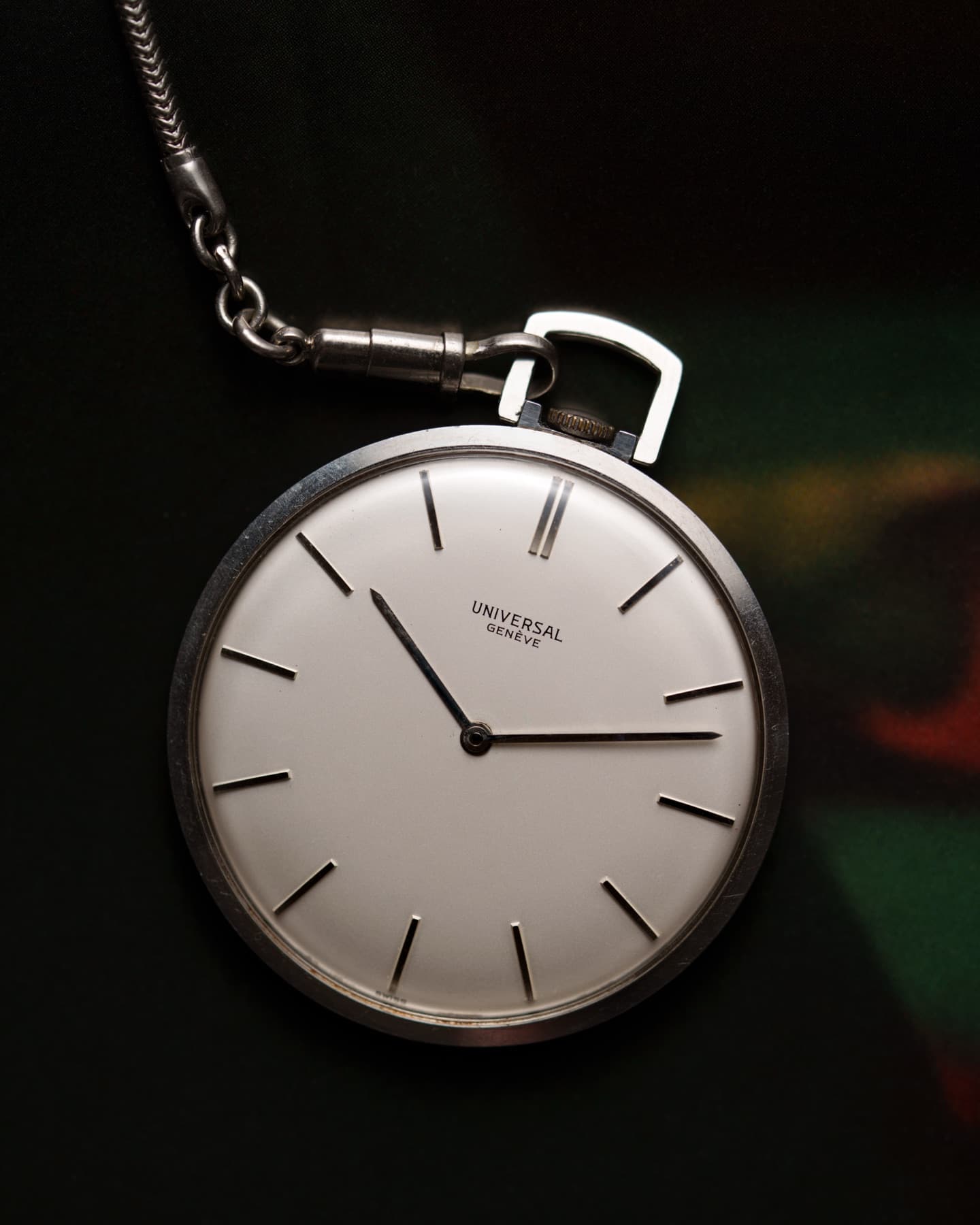 Vintage open-face pocket watch with silver dial on a dark background